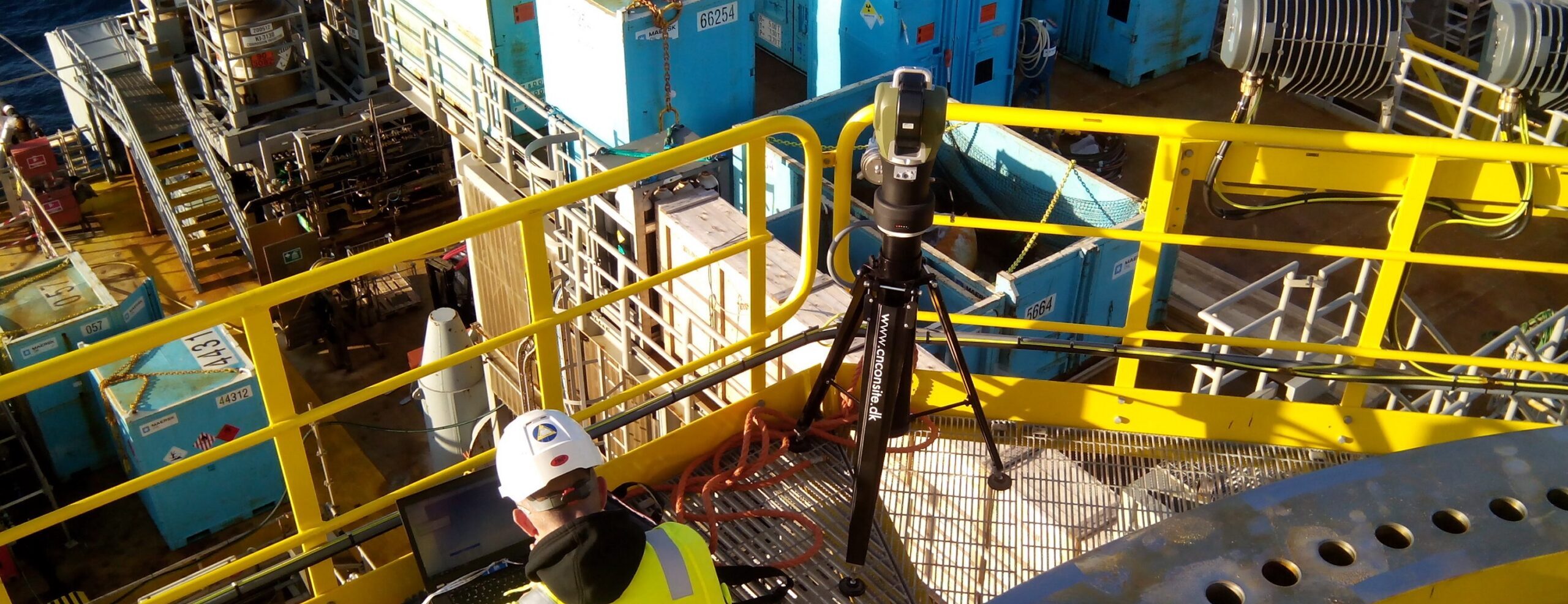 Technician operating a 3D laser tracker measuring a large industrial flange offshore